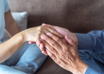Cropped high angle shot of unidentifiable man and woman holding hands sitting on sofa